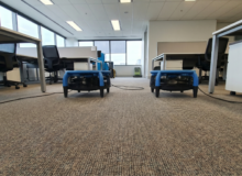 Profesjonalne pranie wykładziny biurowej w&nbsp;Warszawie – dwa niebieskie osuszacze Dri-Pod podczas pracy na&nbsp;świeżo wyczyszczonej podłodze.